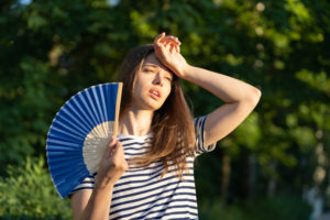 Face à la chaleur de l'été, une femme utilise un éventail pour s'aérer